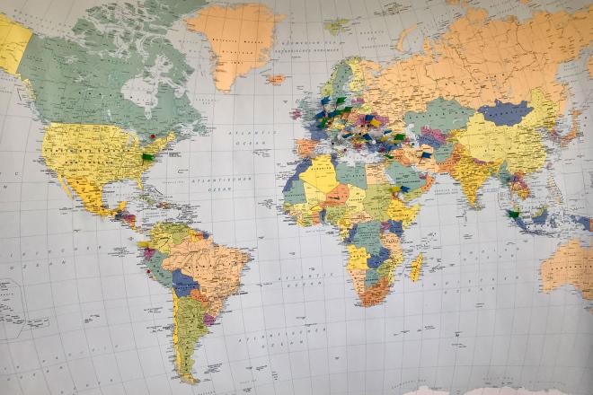Eine bunte Weltkarte mit Flaggennadeln, die das Herkunftsland markieren.