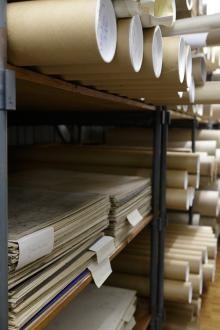 Regal mit Akten, zum Teil in Mappen, zum Teil in Papprollen