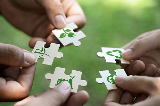 Fünf Hände halten Puzzle mit unterschiedlichen Symbolen darauf.