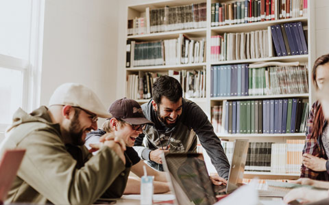 Junge Menschen schauen gemeinsam auf den Bildschirm eines Laptops
