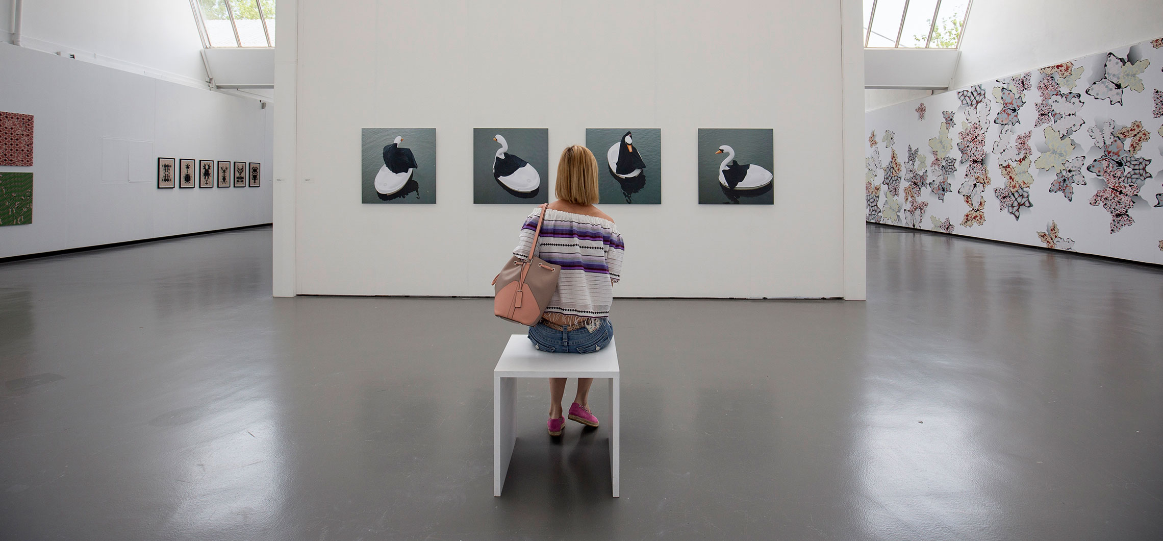 Eine Frau sitzt in der Kunsthalle Göppingen vor vier Bildern