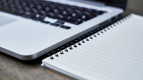 Ein geöffnetes Notebook steht neben einem leeren Block.