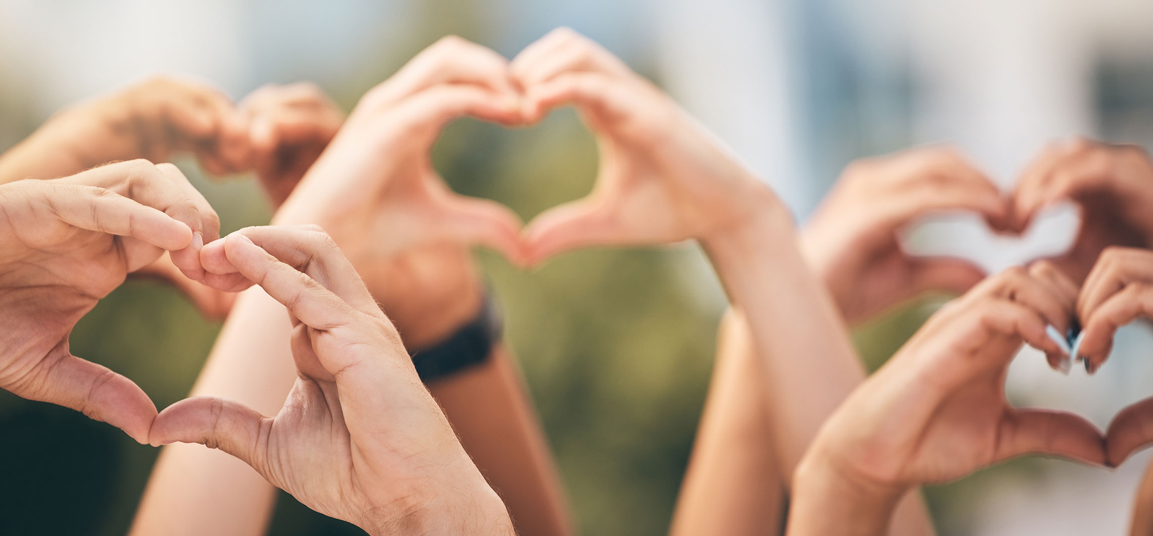 Mehrere Menschen strecken ihre Hände in die Höhe und formen ein Herz.
