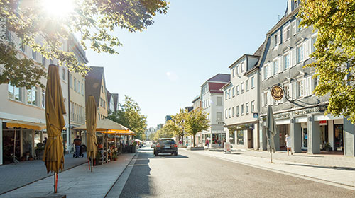 Die Göppinger Hauptstraße im Sommer. Der Himmel ist blau, ein einzelnes Fahrzeug fährt auf der Straße.