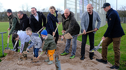 Zahlreiche Menschen mit Schaufeln in der Hand führen einen Spatenstich durch.