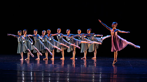 Zahlreiche Balletttänzerinnen auf einer Bühne.