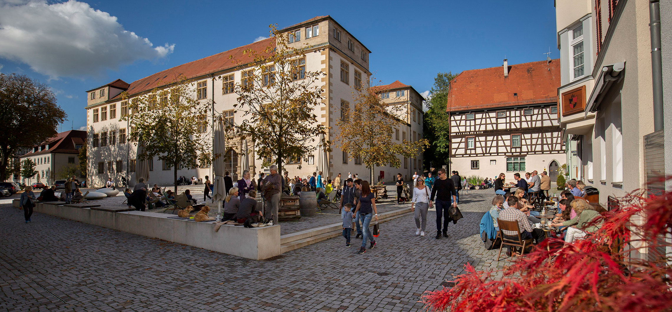 Der Schlossplatz in Göppingen im Sommer, viele Menschen queren den Platz oder sitzen in einem Cafe.