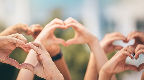 Mehrere Hände formen das Herz-Zeichen, das in die Luft gestreckt wird.