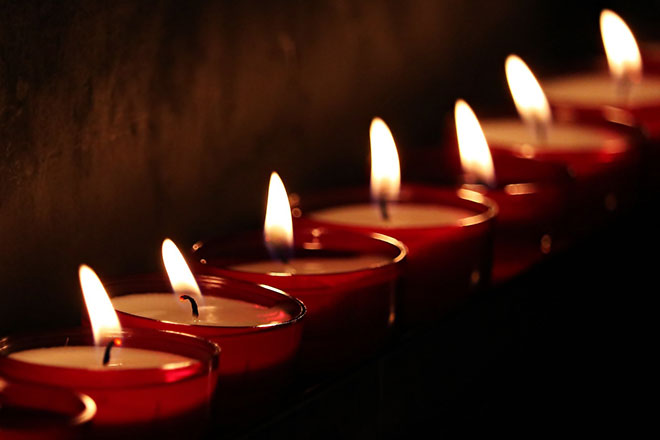 Mehrere Trauerkerzen stehen entzündet nebeneinander.