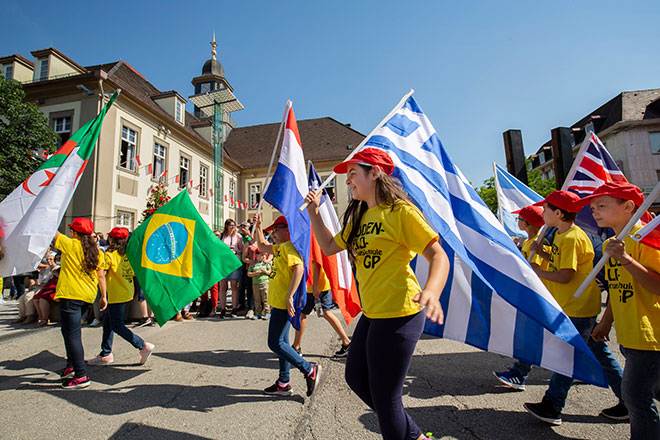 Kinder tragen unterschiedliche Landesfahnen während des Maientagsumzugs