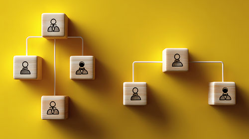 Mehrere Holzwürfel mit Piktogrammen von Menschen stehen verbunden nebeneinander.