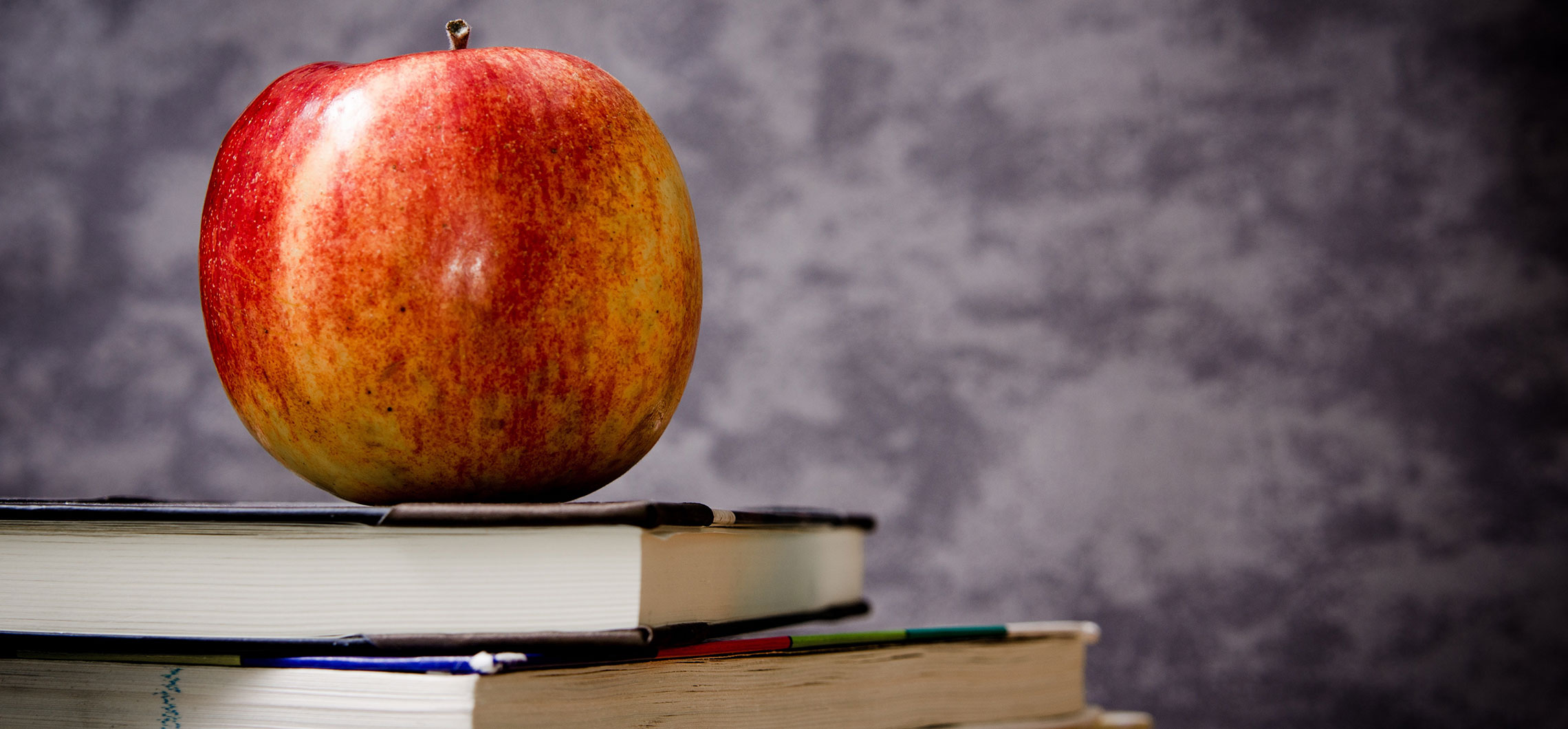 Ein roter Apfel steht auf einem Stapel von Büchern.