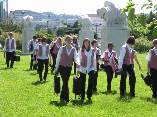 Musikschülerinnen und Schülern in Uniform laufen über eine grüne Wiese.
