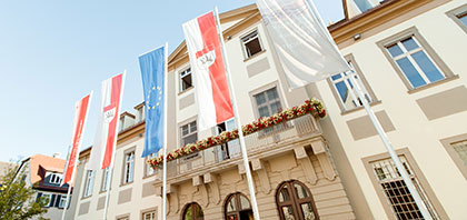 Das Göppinger Rathaus im Sommer. Fünf Fahnen wegen vor dem Gebäude.