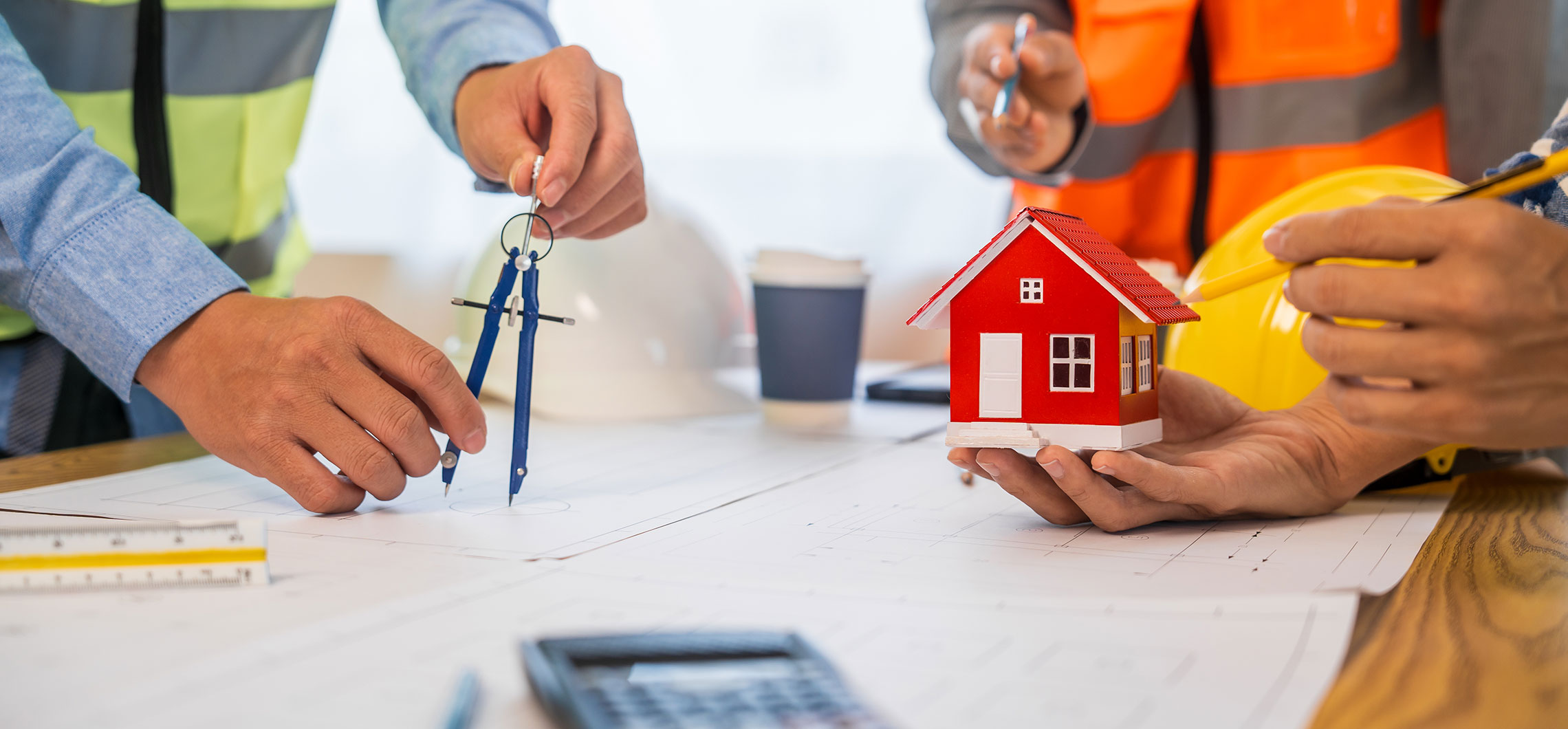 Mehrere Personen stehen um einen Tisch mit Bauplänen