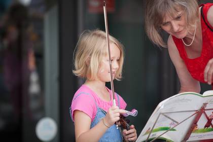 Eine junge Geigenspielerin mit ihrer Lehrerin vor einem Notenständer