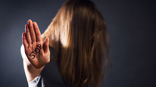 Eine Frau hält ihre Hand in die Kamera, auf ihrer Handfläche steht STOP.
