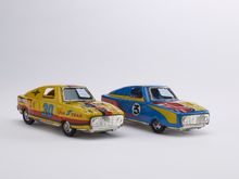 zwei verschieden farbige Spielzeugautos aus Blech